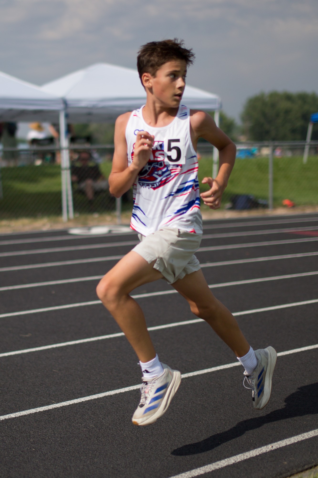 A DASH runner in a white team singlet running on the track